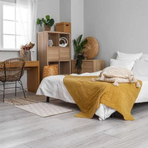 A contemporary bedroom featuring sleek, wooden plank flooring by Payless Floor Coverings.